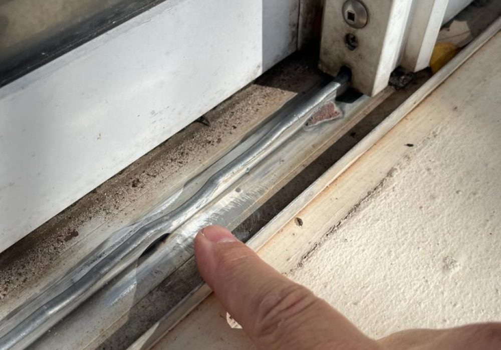 Worn, wavy sliding glass door track in need of repair